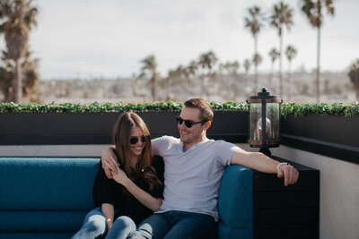 Couple holding hands on rooftop with palm trees in frame during San Diego engagement session