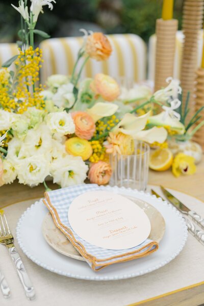 "Elegant wedding reception table setting in San Diego, featuring a soft floral centerpiece, a menu card with a vintage design, and fresh lemons for a pop of color. Felisha, a New England-based destination wedding photographer, specializes in capturing timeless moments and beautiful wedding details in San Diego, New England, and worldwide locations.