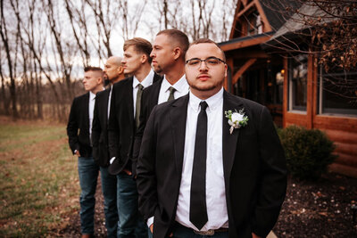 Groom and groomsmen in suits lined up for portrait