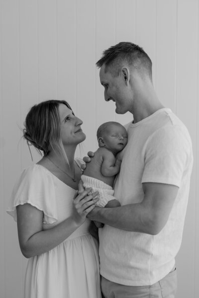 woman holding baby smiling at camera neutral colors