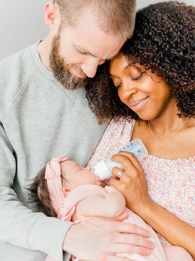 Husband gently pMother and father smiling at newborn in Massachusetts Newborn Photography session