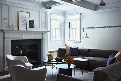 Interior design companies in Boston redesigned a historic home in Concord with traditional architecture, a fireplace and coffered ceiling, plus modern lighting, furniture, and art.