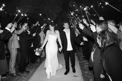 A newlywed couple walking through a tunnel of their guests smiling