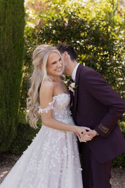 Candid wedding photo of a couple laughing together outdoors.
