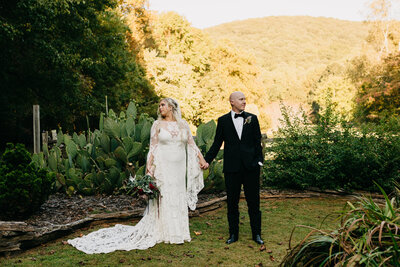 Bride & Groom holding hands in front of hilly landscape