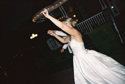 bride holding grooms hand while walking into wedding reception space