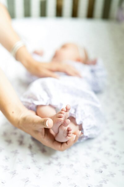 Close-up of newborn feet held by mother in crib during a luxury in-home session