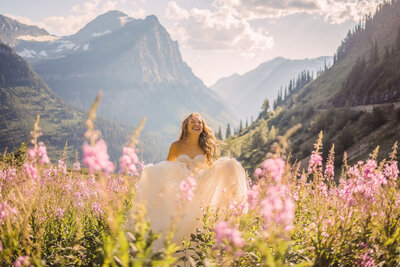 Senior girl with a long glittery ball gown on laughing and running through a tall field of purple flowers with the large mountains in the background