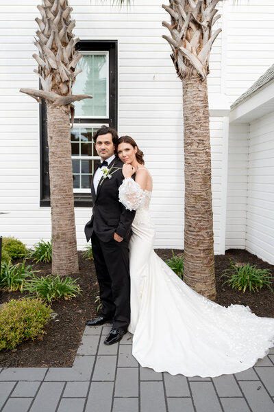 Portrait of Bride and Groom infront of white church and palm trees. During their wedding. 