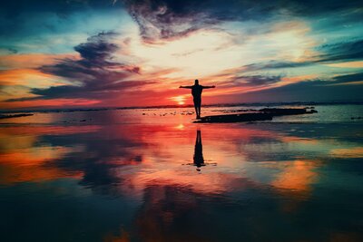 A person successfully completed the Complete Health Program is standing in front of a sunset