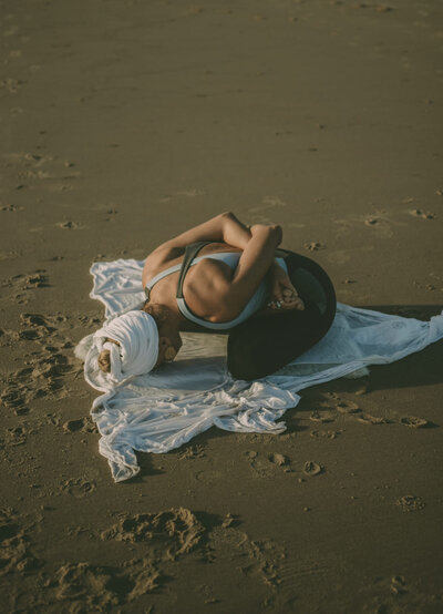HarJiwan in a yoga pose on the sand
