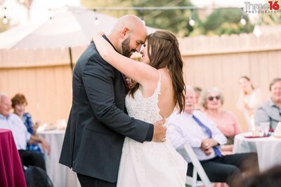 Bride and Groom share a tender moment during their first dance with guests watching