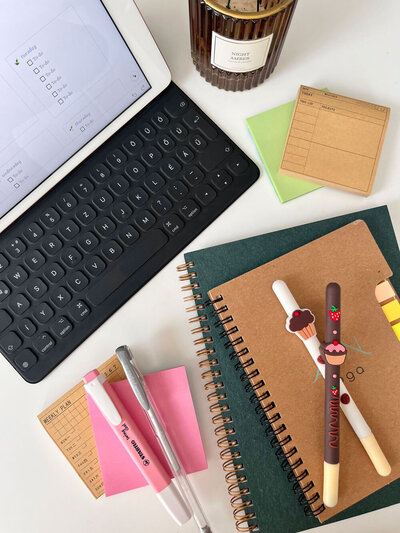 A bird's eye view of an iPac, keyboard, notebooks and notepads on a desk