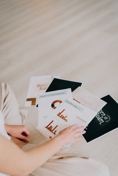 Hands flipping through financial papers laid out on the floor