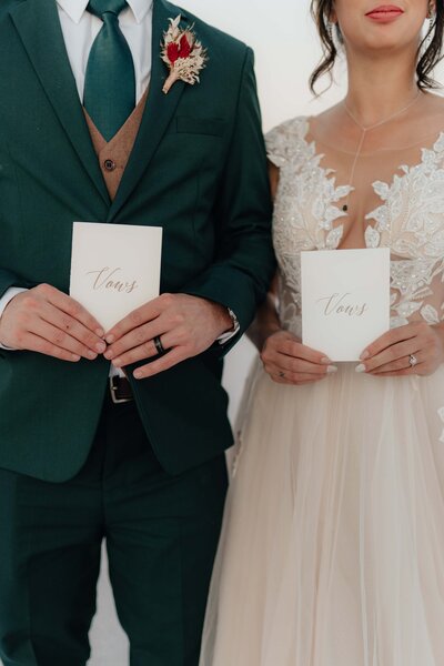 couple in wedding clothes holding vow books