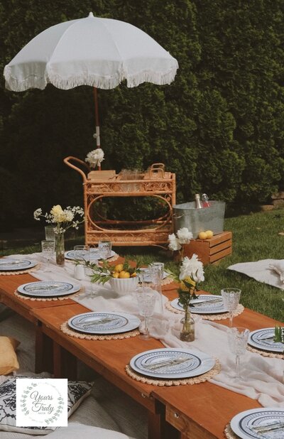 Elegant backyard picnic table with patterned plates, crystal glassware, and fresh floral accents, styled by Yours Truly, a wedding planner and designer in New Jersey