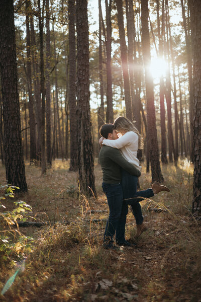 A man lifts his fiance during a golden hour sunset at Congaree Park in Columbia, SC.