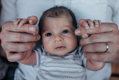 Newborn photography session with young baby wearing a white and grey onesie.