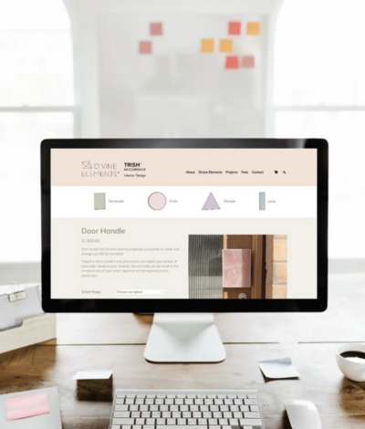 mac computer showing interior designer website on a timber desk with a pinboard with colourful sticky notes in the background