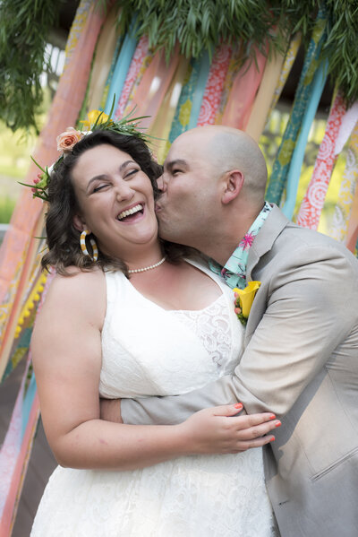 A person kissing their partner's cheek as they hug them on their wedding day 
