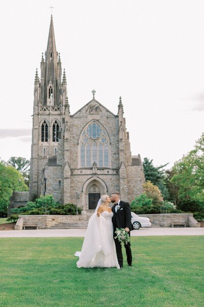 bride and groom kissing in front of historic chapel