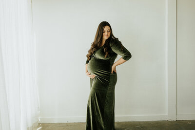 A pregnant woman poses gracefully during her maternity shoot in Longmont, Colorado, showcasing her baby bump in a serene and intimate moment.