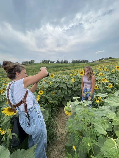 Hey an iPhone image of heidi iliff photographing a senior in high school inside of a field at sunset.