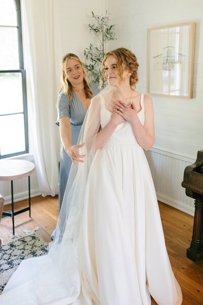 Bridesmaid adjusting bride's dress at timeless Nashville wedding