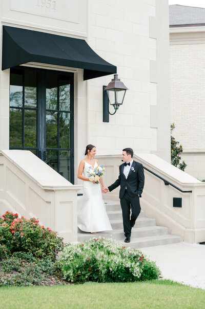 Bride and groom walking down front steps at Lakeside Country Club in Houston