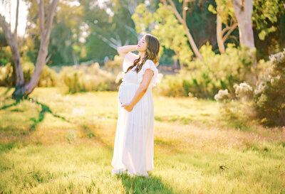 A gorgeous expecting mother modeling for her Rancho Santa Fe maternity photography session in a field