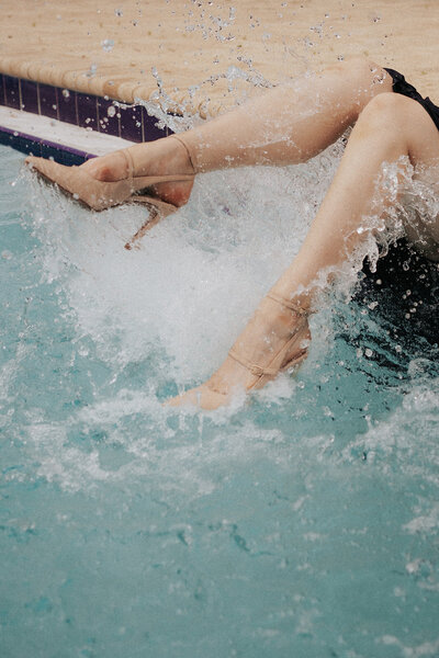 woman kicks high heels in pool