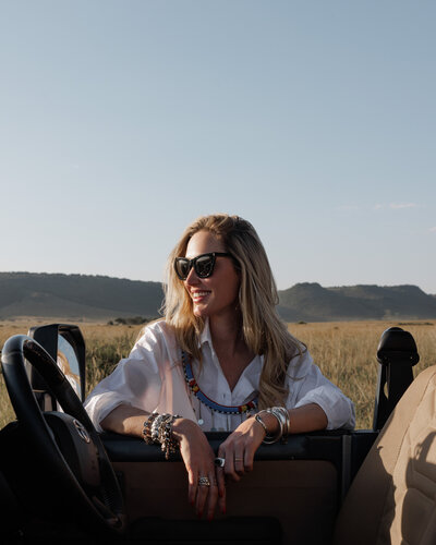 Alexis, founder of House of Imara, smiling in an open-top safari vehicle with wide savanna views.