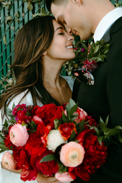 A bride and groom forehead to forehead smiling with a bouquet of flowers in Austin Texas