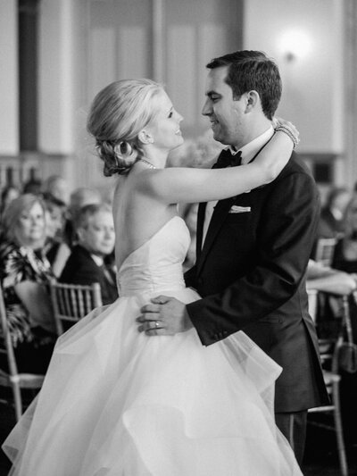 A classic black and white wedding photo capturing a newlywed couple’s intimate first dance, filled with emotion and elegance.