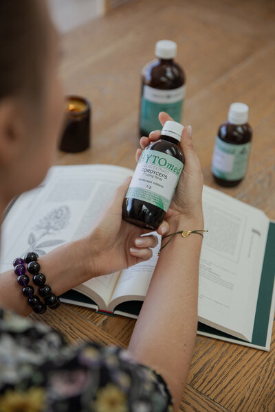 Naturopath Lauren Glucina at work, holding a bottle of liquid herbs as she decides which to include in a client formula.
