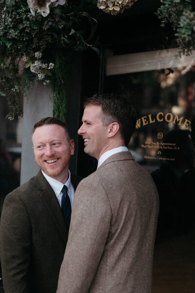 Chris and Dave walking hand in hand and laughing together outside Quirk Hotel, captured with movement and emotion in natural light.