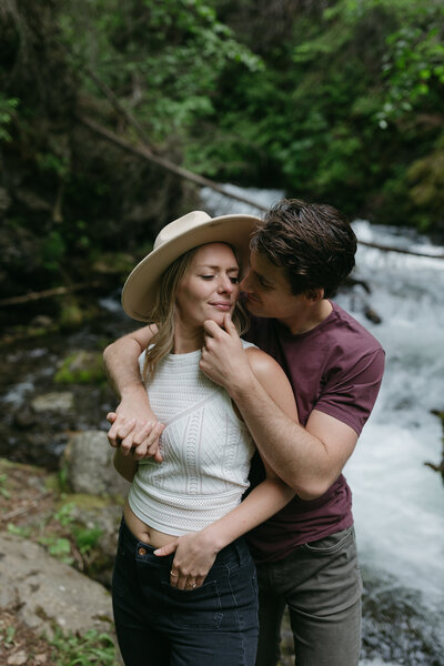 A couple snuggled next to a waterfall in Alaska. 