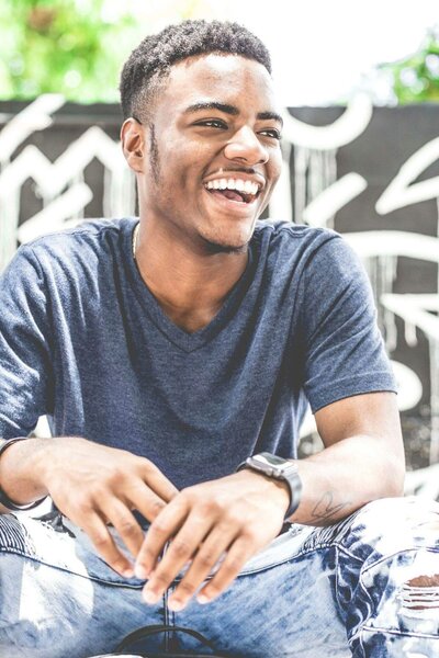 Black teen male smiling in blue shirt and jeans