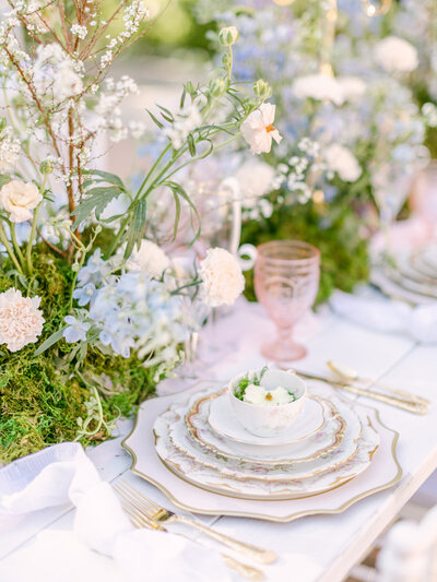 Wedding table set with stacked plates, glassware, silverware, and floral accents
