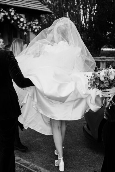 bride walking with her dress pulled up from behind