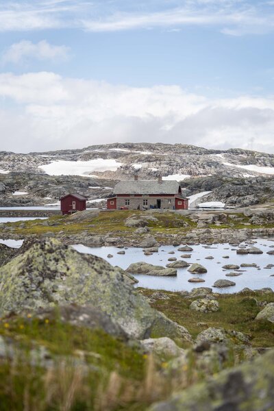 A red Norweigan cabin in the middle of the Hardangervidda wilderness next to a beautiful river.