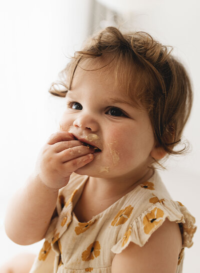 Messy hands and frosting face – candid cake smash moment in Poole photography studio