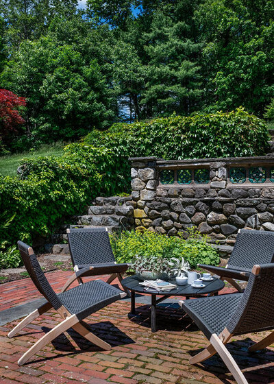 Boston interior designer, Sarah Scales, renovates a historic Concord home patio with classic columns, original brick pavers, and views of a mature garden.