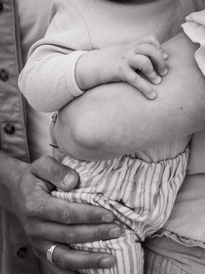 Detailfoto van handen de de verbinding tussen de gezinsleden laat zijn tijdens een fotoshoot