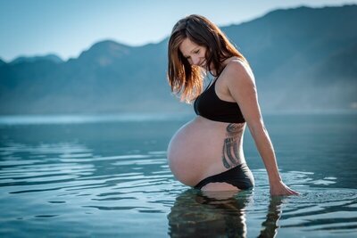 a pregnant woman standing in the water in her bikini during her maternity session in Queenstown