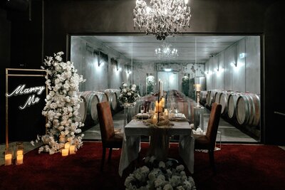 Romantic indoor proposal table setup with candles, flowers, and rose petals in Auckland, captured by Zanthe Vorsatz Photography.
