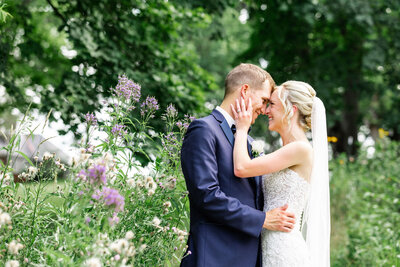 Bride Holds Groom's Face During Embrace in Flower Field at Robin Hill Park