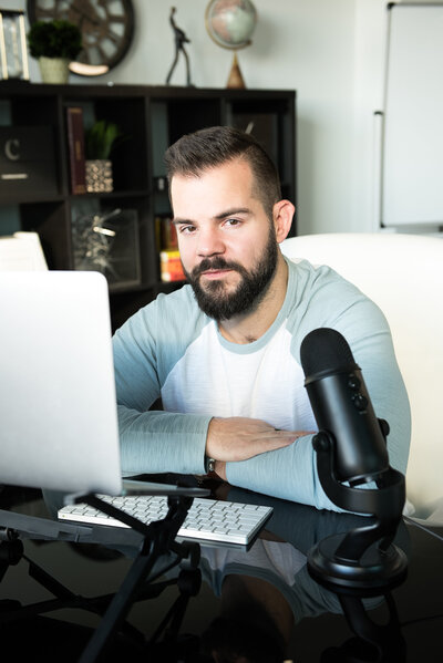 Man sitting at desk with computer and podcasting microphone
