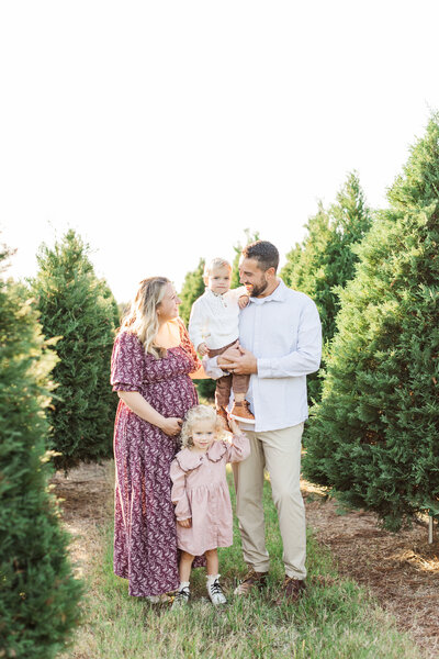 family of four smile at each other in houston tree farm