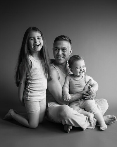Black and white studio portrait of father and  2 kids dark and moody stunning photo
